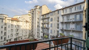 A multi-story residential building with balconies, terracotta roof tiles, and a clear sky.