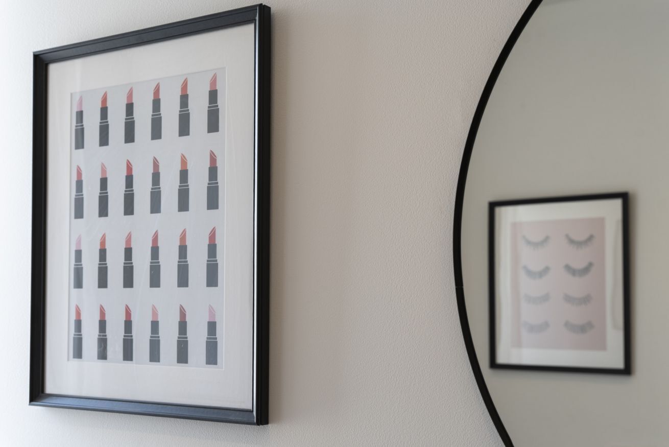 A framed picture of lipstick on a wall.