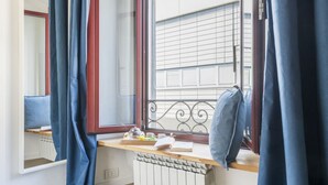 A room with a window, curtains, a radiator, a wooden table with a tray, and a chair. - Easylife - Soak up the Crisp, Minimal Vibe at a Light-Filled City Oasis (Milano)