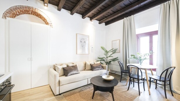 A modern living room with a white sofa, a round coffee table, and a dining area with chairs. - Easylife - Soak up the Crisp, Minimal Vibe at a Light-Filled City Oasis (Milano)