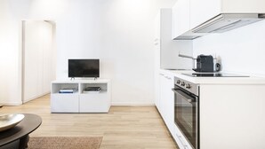 A modern kitchen with white cabinetry, a built-in oven, and a flat-screen TV on a white console. - Easylife - Soak up the Crisp, Minimal Vibe at a Light-Filled City Oasis (Milano)
