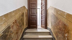 Un escalier aux murs de marbre et aux portes en bois menant à une pièce.