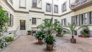 Une cour intérieure agrémentée de plantes en pot et un escalier menant à l’entrée.