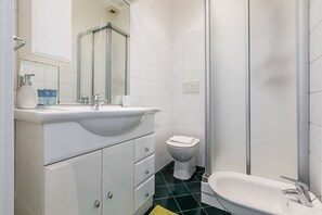 A bathroom with a white sink, a toilet, and a shower.