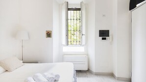 Hotellihuone, jossa on sänky, ikkuna, josta avautuu näkymä vehreään maisemaan, patteri ja seinälle asennettu televisio.