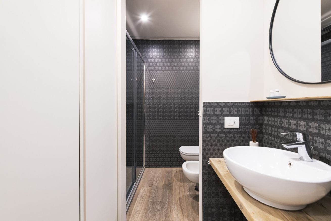 A modern bathroom with a wooden vanity, a white sink, and a toilet.