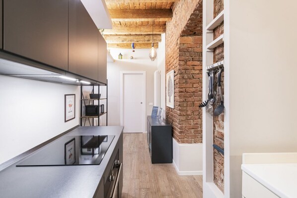 A modern kitchen with a sleek countertop, a black stove, and a brick accent wall.