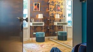 A room with a large mirror, a small table, and two ottomans.