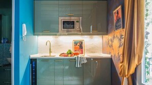 A modern kitchen with a microwave, sink, and a decorative wall with a poster.