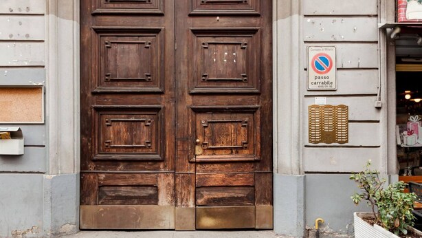 A large wooden double door with a metal threshold, a no parking sign, and a small plant beside the door. - Easylife - Apartment with a refined style (Milano)