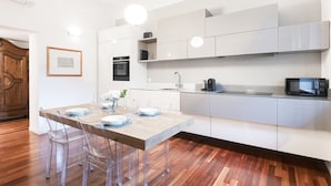 A modern kitchen with white cabinets, a wooden dining table, and a built-in oven. - Easylife - Oasis of comfort&style in Porta Romana (Milano)