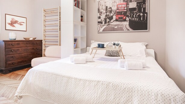 A neatly arranged bedroom with a bed, a wooden wardrobe, a bookshelf, and a framed picture on the wall. - Easylife - Oasis of comfort&style in Porta Romana (Milano)