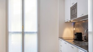 A modern kitchen with white cabinets, a black countertop, and a built-in microwave. - Easylife - Modern and new flat in Duomo area (Milano)