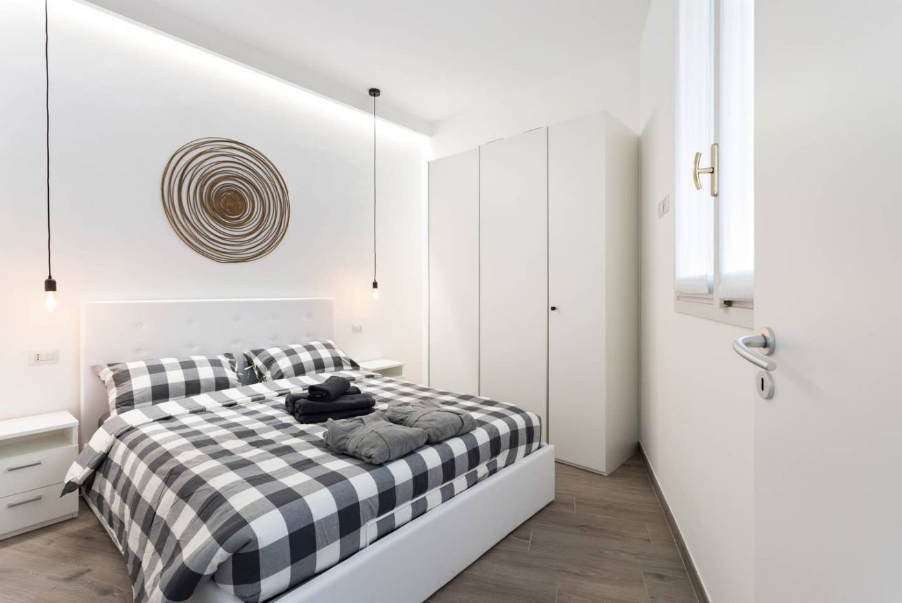 A modern bedroom with a checkered bedspread, a circular wall decoration, and a wardrobe.