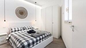 A modern bedroom with a checkered bedspread, a circular wall decoration, and a wardrobe. - Easylife - Modern and new flat in Duomo area (Milano)