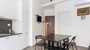 A modern kitchen with white cabinets, a black countertop, and a dining table with four chairs. - Easylife - Modern and new flat in Duomo area (Milano)
