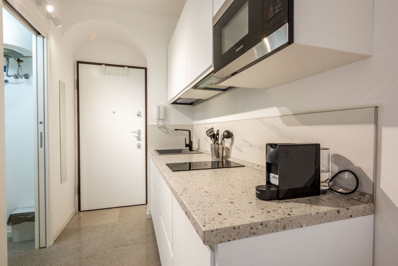 Una cocina moderna con microondas integrado, cafetera y un lavabo.