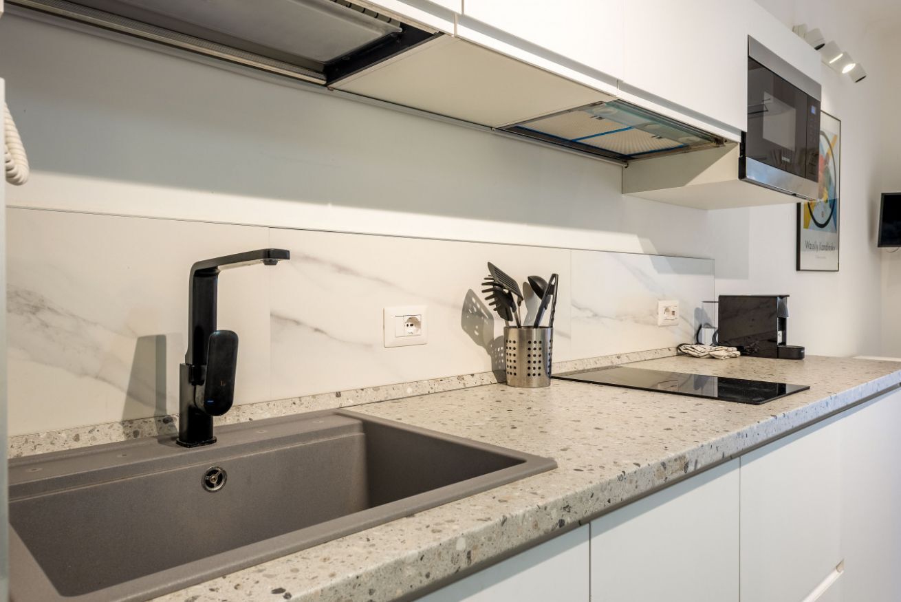 A modern kitchen with a large sink, a built-in stove, and a microwave.