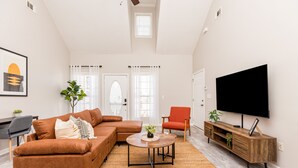 Una sala moderna con un sofá seccional, una mesa de centro, un televisor y un sillón rojo.