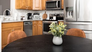 Una cocina moderna con armarios de madera, electrodomésticos de acero inoxidable y una mesa de madera oscura con un jarrón de flores.