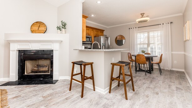 Una cocina moderna con chimenea, taburetes de madera y un comedor con mesa y sillas.