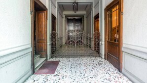 Un pasillo con suelo de baldosas, puertas de madera y una reja de hierro forjado.