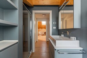 A modern bathroom with a large mirror, a white sink, and a wooden ceiling. - Easylife - Elegant three-room apartment in the Porta Venezia area (Milano)