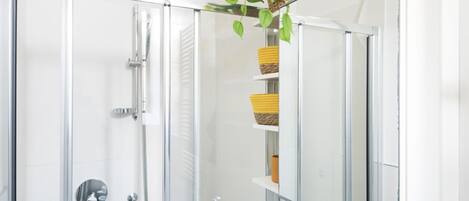 Een moderne badkamer met een douchecabine van glas, een spiegel en planken met gevlochten manden.