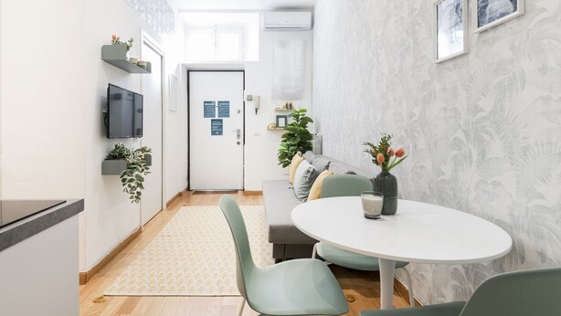 Ett modernt kök med matplats, en platt-TV och ett litet matbord med stolar.