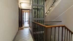 A narrow hallway with tiled flooring, a wooden handrail, and a glass door leading to another room. - Easylife - Intimate retreat in Porta Venezia (Milano)