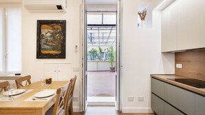 Une cuisine moderne avec une table à manger en bois, des chaises et une vue sur un espace extérieur agrémenté de plantes.