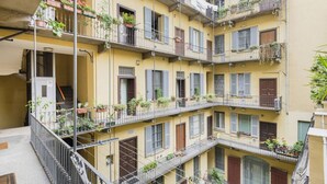 Un immeuble à plusieurs étages doté de balcons, chacun étant agrémenté de plantes en pot.