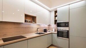 Une cuisine moderne avec des meubles de couleur claire, un plan de travail en bois, un four encastré et un four à micro-ondes.