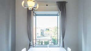 A dining area with a table and chairs, a window with curtains, and a hanging light fixture.