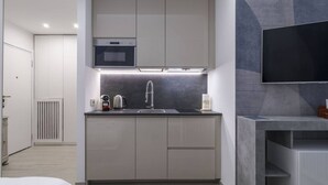 A compact kitchen with a built-in oven, a sink, and a microwave. - Easylife - Style and comfort in Porta Venezia (Milano)