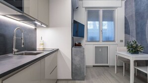 A modern kitchen with a built-in stove, a sink, and a window overlooking a cityscape. - Easylife - Style and comfort in Porta Venezia (Milano)