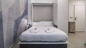 A modern hotel room with a bed, a wardrobe, and a nightstand. - Easylife - Style and comfort in Porta Venezia (Milano)