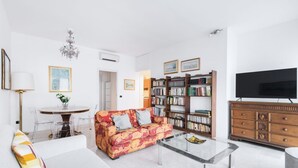 A living room with a sofa, coffee table, bookshelf, and a television.