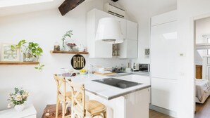 Eine moderne Küche mit weißen Schränken, einer zentralen Kochinsel mit Barhocker und einer Pendelleuchte.