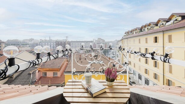 Eine Dachterrasse mit Blick auf die Stadt, mit einem Tisch, einem Buch und einem Blumenstrauß.