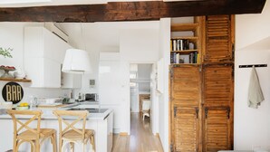 Eine moderne Küche mit weißen Schränken, Holzstühlen und einer Holztür zu einem anderen Raum.