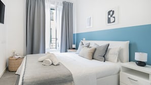Une chambre bien rangée, avec un lit, une table de chevet et une vue sur l’extérieur.