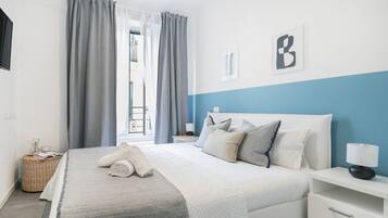 Un dormitorio ordenado con cama, mesita de noche y vistas al exterior.