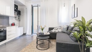 A modern kitchen with white cabinets, a black stove, and a dining area with a round table and chairs.