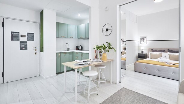 A modern, well-lit apartment with a kitchen, dining area, and a bedroom.