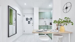 A modern kitchen with white cabinets, a wooden countertop, and a yellow vase with green plants.