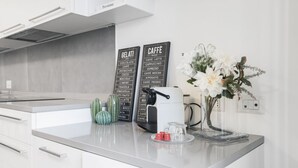 A modern kitchen counter with a coffee machine, two chalkboards listing gelati and cafe options, a vase with flowers, and a decorative cactus. - Easylife - Beautiful flat in Porta Romana (Milano)