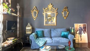 A living room with a grey sofa, a glass coffee table, and decorative mirrors on the wall.