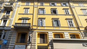 A multi-story building with a yellow facade, multiple windows with shutters, and a sign for 'L'ITALIANO' restaurant.