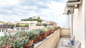 Un balcon agrémenté de plantes en pot, d’une chaise et d’une lanterne bleue.